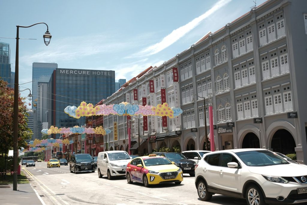 Cars drive down a street lined with buildings.