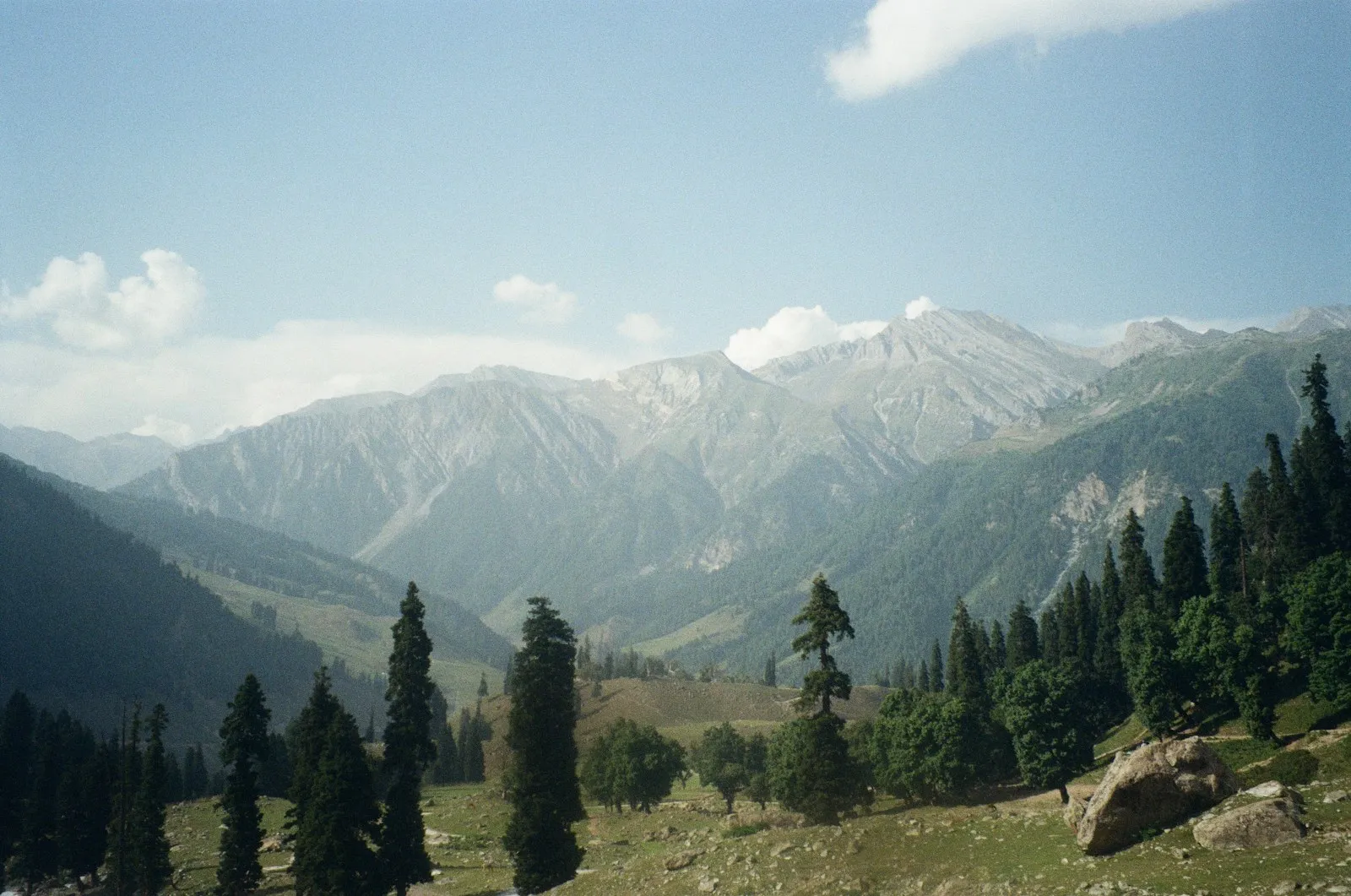 Photo by Pavithra Sundar a view of a mountain range with trees in the foreground